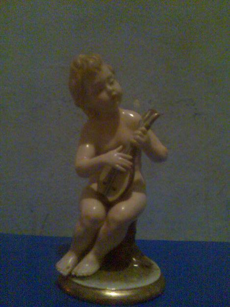 figura antigua de un niño desnudo tocando una guitarra pequeña